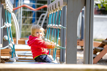 Kleinkind spielt auf dem Spielplatz an einem Klettergerüst