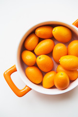 tasty kumquat in orange plate isolated on white background