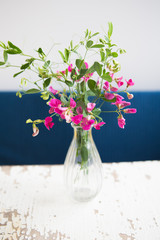very beautiful little pink flowers in a vase on an old table