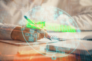 Cryptocurrency hologram over woman's hands writing background. Concept of blockchain. Double...