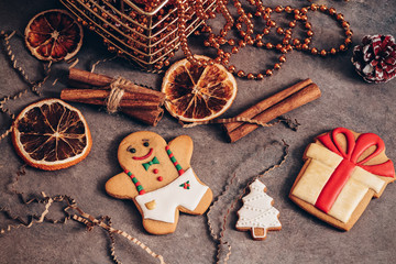 Festive christmas composition with gingerbread man in vintage style, dark rustic background.Flat-lay of glittering toys, cinnamon, dried orange slices