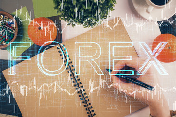 Forex chart hologram on hand taking notes background. Concept of analysis. Double exposure