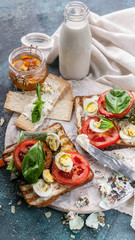 Cereal toasts with cheese, fresh tomatoes, basil leaves and quail eggs. Tasty and healthy breakfast concept. Vertical shot