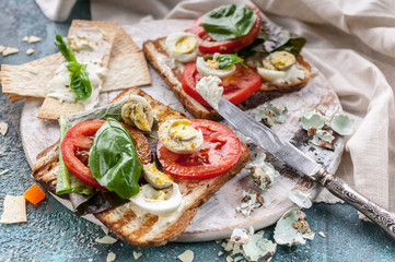 Close-up Italian toasts with cheese, tomatoes, basil, quail eggs. Ideas for a tasty and healthy breakfast.