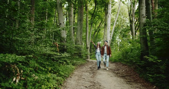 Couple of young tourists walking in mountain path and talking, active lifestyle and recreation