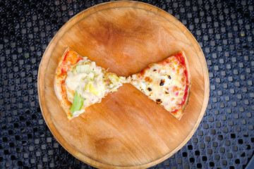 Close-up, two pieces of hot pizza with cheese  in a cafe on a wooden background.