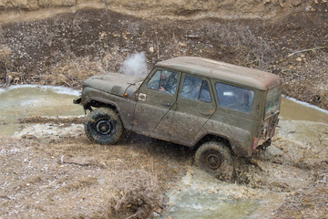 Obraz na płótnie Canvas Rally on Russian SUVs in the mud in winter, Trapped all-terrain vehicle pulled out of the river 