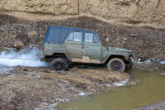 Rally on Russian SUVs in the mud in winter, Trapped all-terrain vehicle pulled out of the river	