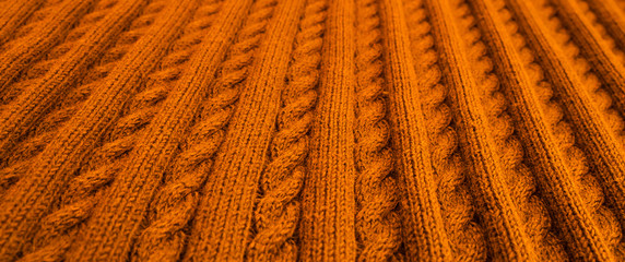 Plaid, knitted pigtail. Autumn colors. Wool texture for background. Soft focus.