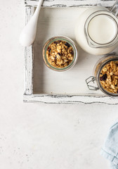Granola in glass jars with raisins and milk. Healthy breakfast.