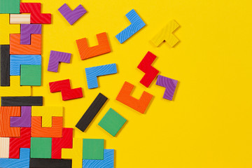 Different colorful shapes wooden blocks on yellow background. Top view