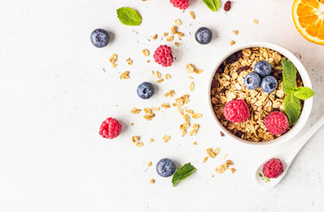Healthy breakfast ingredients. Bowl of homemade granola with milk, fresh berries (blueberry and raspberry), orange and milk. 