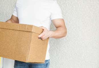 Delivery strong, muscular man loading cardboard boxes for moving to an apartment. professional...