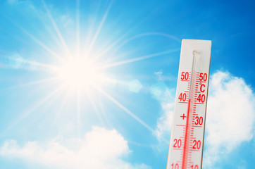 Thermometer is hot in the sky bright sun, glowing rays, concept of extreme weather.