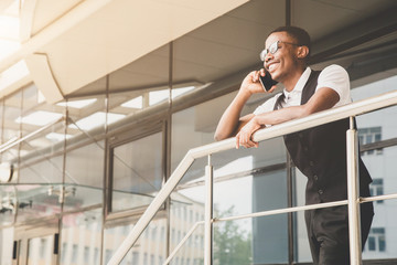 Young african american business man in suit and eyeglasses talking on the phone on the background of the business center