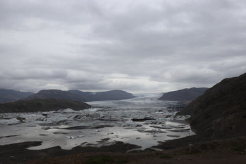 front view of a glacier and lake under a cloudy sky 