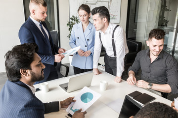 A team of young businessmen working and communicating together in an office. Corporate businessteam and manager in a meeting.