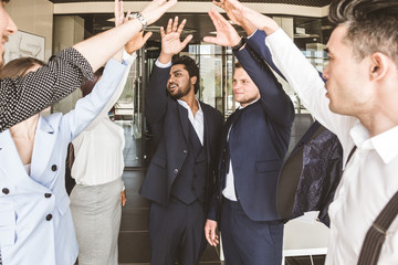 Close up top view of young people putting their hands together. A team of young businessmen working and communicating together in an office. Corporate businessteam and manager in a meeting.