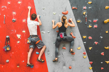 couple of athletes climber moving up on steep rock, climbing on artificial wall indoors. Extreme...