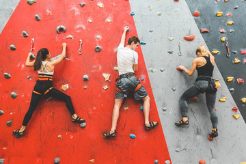 Athletes climber moving up on steep rock, climbing on artificial wall indoors. Extreme sports and...