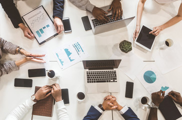 A team of young office workers, businessmen with laptop working at the table, communicating...