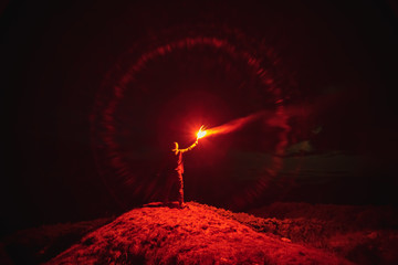 The man with a red firework stick standing on a mountain. evening night time - Powered by Adobe