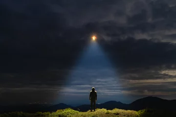 Foto op Canvas De UFO schijnt op een mannetje dat op de berg staat © Artem