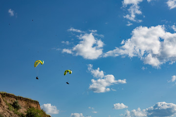paraglider flying in the blue sky among the white clouds. Paragliding