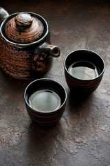 Asian tea bowls and teapot  on  dark stone table