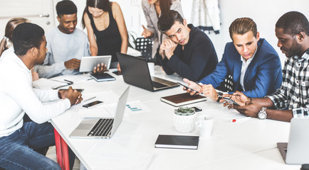 A team of young office workers, businessmen with laptop working at the table, communicating together in an office. Corporate businessteam and manager in a meeting. coworking.