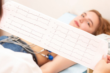 The doctor cardiologist looks at the printout of the cardiogram of patients, which lies on the...