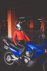 Fototapeta na wymiar Sexy woman in a red leather jacket sits on a sports bike