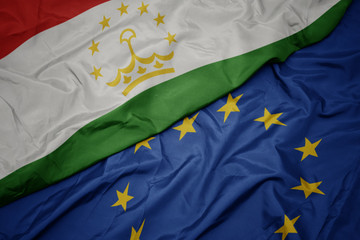 waving colorful flag of european union and flag of tajikistan.