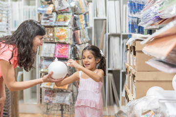 Mother an daughter playing with white polystyrene spheres and figures