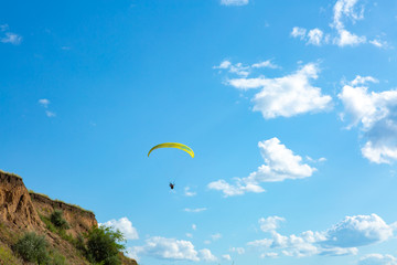 paraglider flying in the blue sky among the white clouds. Paragliding