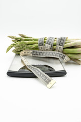 Asparagus surrounded by a medical tape on weighing scale for diets