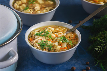 Healthy Chicken Noodle Soup Bowl with Condiment. Dish of Warm Starter with Spoon. Vegetable Bouillon with Pasta and Potato Elevated View. Pot on Kitchen Table Closeup. Catering Concept