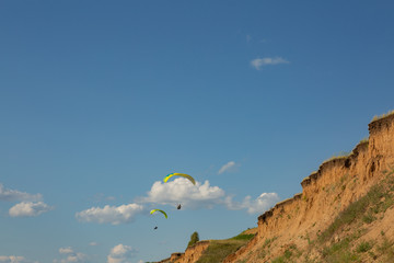 paraglider flying in the blue sky among the white clouds. Paragliding