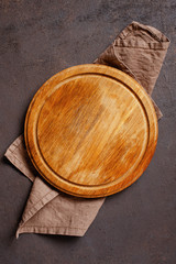 Brown table with empty pizza board and linen napkin