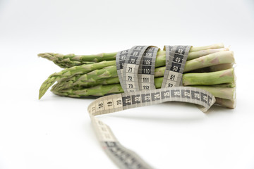 Asparagus surrounded by a medical tape on weighing scale for diets