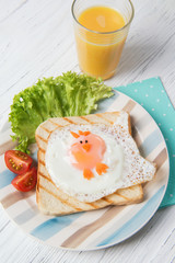 Funny toast with fried eggs in a shape of chicken and orange juice, healthy food for kids Easter idea