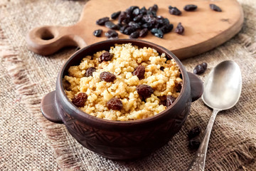 Sweet millet porridge with dark raisins in ceramic rustic bowl