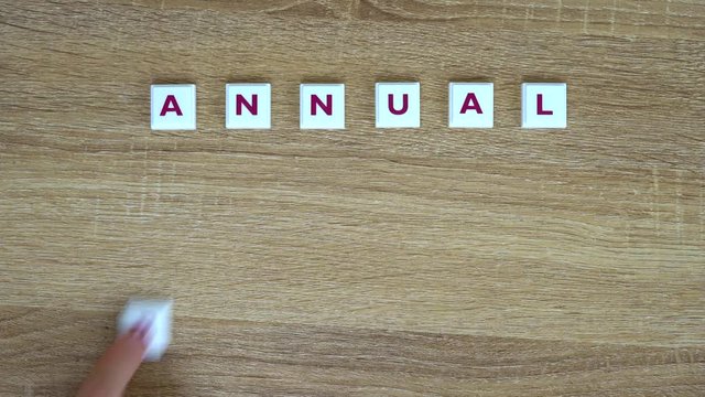 Phrase "annual report" is made up of letters on a wooden background. Design for presentation of business idea, startup, report. Phrase "annual report" is written from letters on table. Video saver.