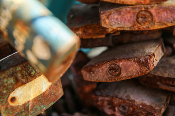 A detail of several old and rusty locks hanging on a handrail on a bridge. 