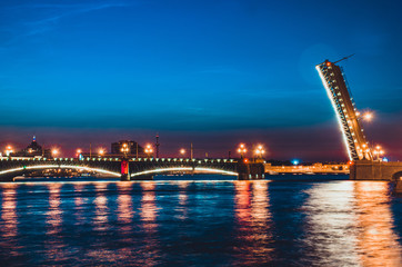Fototapeta na wymiar A famous illuminated drawbridge in Saint Petersburg at night with lights reflected in water. Trinity or Troitskiy bridge. Travelling to Russia well-known sight. Beautiful night river view.