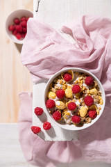 Healthy breakfast table concept. Plate with oatmeal cereal flakes and raspberries on a light wooden surface