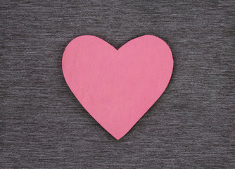 Wooden heart shape, on gray material, as a background texture with design space.