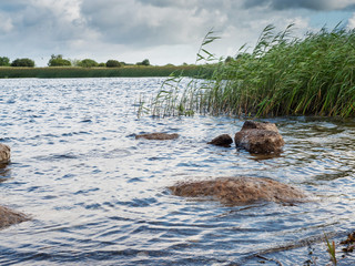 Rural landscape, River bank, Cloudy sky. Warm sunny day. Nature concept.