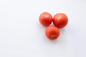 three tomatoes on the white surface