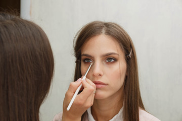 The process of creating makeup. Makeup artist working with a brush on the face of the model.